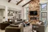 Inviting living area with elegant stone fireplace, modern chandelier, and open-plan kitchen, perfect for stylish entertaining.