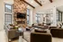 Luxurious living room with a high stone fireplace wall, plush seating, and large windows offering a cozy and elegant ambiance.