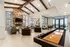 Luxurious lounge with high ceilings, exposed beams, stone fireplace, and shuffleboard table for entertainment.