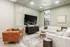 Elegant living room featuring a plush white sectional sofa, stylish caramel leather armchair, and a large wall-mounted TV, set against soothing mint green walls.