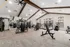 Spacious and modern fitness center featuring state-of-the-art gym equipment, high ceilings with exposed beams, and large windows for ample natural light.