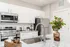 Modern kitchen with sleek stainless steel appliances, elegant granite countertops, and stylish white cabinets enhanced by tasteful decor and a potted plant centerpiece.
