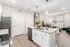 Modern open-concept kitchen with sleek granite countertops and stylish pendant lighting, leading into a cozy, well-lit living area with large windows.