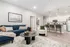 Modern living room with elegant decor featuring a plush blue sofa, cozy armchair, and chic kitchen with bar seating.