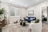 Charming living room featuring a plush blue sofa, cozy white armchair, and stylish decor with soft natural light streaming through large windows.