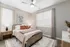 Cozy bedroom featuring a plush bed with stylish pillows, elegant side tables, and modern artwork, illuminated by soft, natural light.