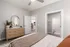 Inviting bedroom with modern decor, featuring a stylish wooden dresser, elegant mirror, and cozy bed leading to an en-suite bathroom.
