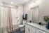 Modern bathroom with elegant granite countertop, sleek white vanity, and a stylish shower area with a curved curtain rod.