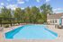 Charming outdoor pool area with crystal-clear water, surrounded by lush trees and stylish lounge chairs, perfect for relaxation.