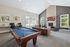 Elegant and spacious lounge area featuring a billiards table, cozy seating by a stone fireplace, and vibrant artwork on the walls, perfect for entertainment and relaxation.