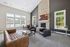 Inviting living room with a stone fireplace, elegant leather seating, and large windows offering abundant natural light and pool views.