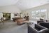 Elegant and spacious apartment lounge featuring a stylish leather sofa, chic seating area, pool table, and natural light streaming through large windows.