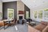 Inviting living room with a cozy stone fireplace, elegant leather seating, and abundant natural light from large windows.