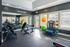 Modern fitness room featuring state-of-the-art gym equipment with natural light streaming in through large windows and a motivational 'No Excuses' sign.