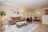 Charming living room with cozy brown sofa, stylish armchair, and elegant decor, adjacent to an inviting dining area.