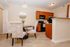 Charming dining area with elegant upholstered chairs and a modern kitchen featuring sleek wooden cabinets and contemporary appliances.