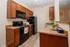 Modern kitchen featuring sleek black appliances, warm wooden cabinetry, and elegant granite countertops.