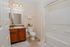 Bright and modern bathroom with elegant fixtures, featuring a granite countertop, spacious mirror, and sleek shower with decorative accents.