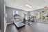 Bright, modern fitness room with large windows, equipped with treadmills and elliptical machines for an invigorating workout experience.
