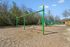 Inviting playground with vibrant green swings, slides, and climbing frames set against a backdrop of lush trees, perfect for outdoor fun and family enjoyment.