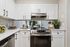 Contemporary kitchen with sleek stainless steel appliances and elegant white cabinetry, featuring stylish decor and plenty of counter space.