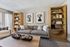 Chic living room with a cozy gray sofa, stylish wooden bookcases, and modern floral art, offering a warm and inviting atmosphere.