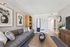 Chic living room with a cozy gray sofa, stylish wall art, modern clock, and elegant decor, offering a warm and inviting atmosphere.