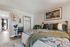 Inviting bedroom featuring a plush bed with stylish throw pillows, artistic wall decor, and abundant natural light from an adjacent hallway.