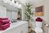 Modern bathroom featuring elegant lighting, vibrant red towels, sleek white vanity, and a stylish potted plant adding a touch of greenery.