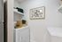 Charming laundry room featuring modern appliances, elegant shelving, and tasteful decor with plant art and woven basket.