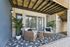 Charming patio setup with cozy wicker chairs, a stylish side table, and lush plants, creating an inviting outdoor living space.