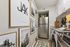 Cozy galley kitchen with modern stainless steel appliances, stylish framed art, and fresh decor.