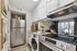 Modern kitchen with sleek stainless steel appliances, vibrant decor, and natural light streaming through sliding glass doors.