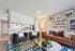 Modern living room with stylish seating, a brown leather sofa, decorative wall art, and an inviting open kitchen space.