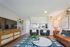 Inviting living room with modern decor featuring a plush leather sofa, stylish armchairs, and a sleek TV unit. Accented with vibrant plants and contemporary artwork for a cozy ambiance.