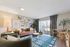 Inviting and stylish living room with a cozy brown leather sofa, modern decor, and lush greenery, accented by natural light streaming through large windows.