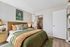 Chic bedroom with cozy green and beige decor, modern artwork, and spacious closet.