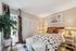 Chic bedroom with vibrant decor, patterned bedding, and a cozy ambiance, featuring a large window with floral curtains and soft lighting.