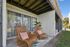 Charming patio with two stylish wicker chairs and a small table, perfect for relaxing in the serene outdoor space.