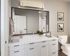 Elegant bathroom interior with a large mirror, white vanity, modern fixtures, and stylish decor.