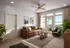 Inviting living room with a cozy leather sofa, elegant wooden floors, and abundant natural light from floor-to-ceiling windows overlooking lush greenery.