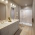Elegant bathroom with dual sinks, modern cabinetry, and a spacious glass-enclosed shower.