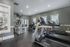 Modern fitness center with state-of-the-art equipment and natural lighting, featuring treadmills, weight machines, and free weights area.