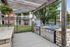 Inviting outdoor BBQ area with modern grills under a rustic pergola, perfect for entertaining in a lush apartment setting.