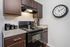 Modern kitchen featuring sleek dark cabinets, a stylish black stove, elegant countertop, and a large wall clock.