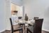 Contemporary dining area with elegant glass table, leather chairs, and a convenient in-unit laundry space.