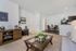 Inviting living room with elegant decor, plush carpet, and open layout leading to a stylish dining area and modern kitchen.