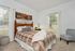 Inviting bedroom with plush bedding, elegant wooden headboard, and modern wall art, offering a serene retreat with ample natural light.