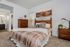 Elegant bedroom with cozy atmosphere, featuring a plush bed, warm wooden furniture, and modern d&eacute;cor art.