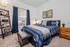 Inviting bedroom with stylish decor, featuring a comfortable bed, contemporary furniture, and a large window allowing natural light.